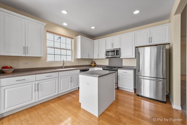 kitchen with sink, white cabinets, stainless steel appliances, and light hardwood / wood-style floors