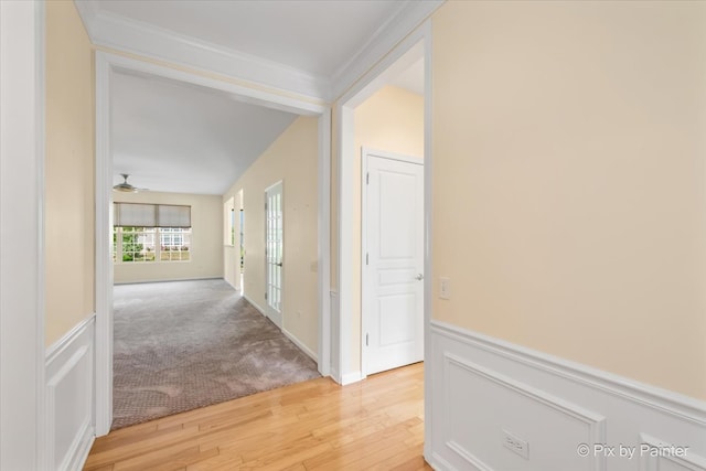 corridor featuring light wood-type flooring, crown molding, and vaulted ceiling