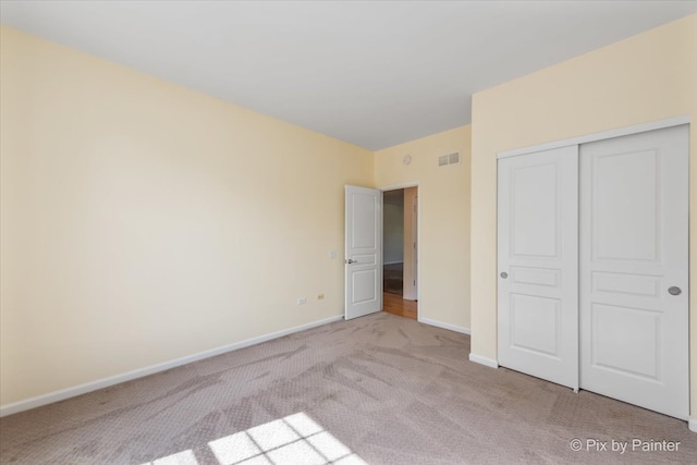 unfurnished bedroom with light carpet and a closet