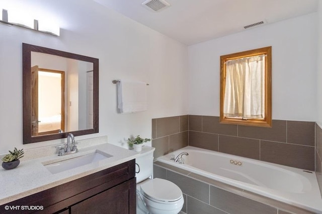 bathroom with a relaxing tiled tub, vanity, and toilet