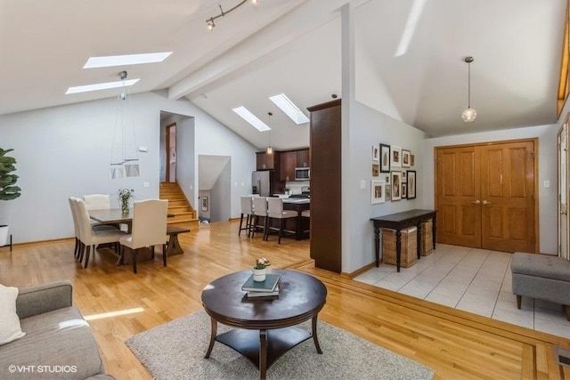 living room featuring beam ceiling, a skylight, high vaulted ceiling, and light hardwood / wood-style flooring