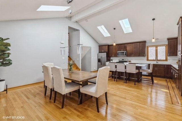 dining area featuring beamed ceiling, high vaulted ceiling, and light hardwood / wood-style floors