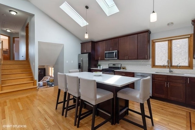 kitchen featuring stainless steel appliances, a center island, hanging light fixtures, and sink