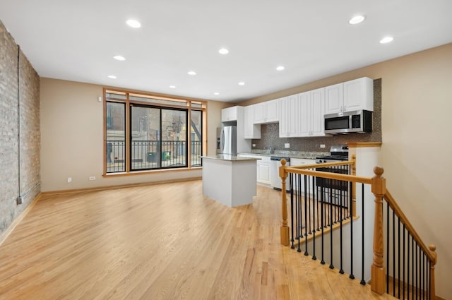 kitchen with white cabinetry, a kitchen island, stainless steel appliances, and light wood-type flooring