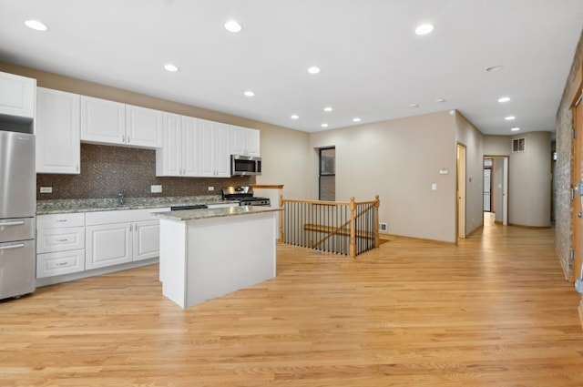 kitchen featuring a center island, stainless steel appliances, white cabinetry, and light hardwood / wood-style floors