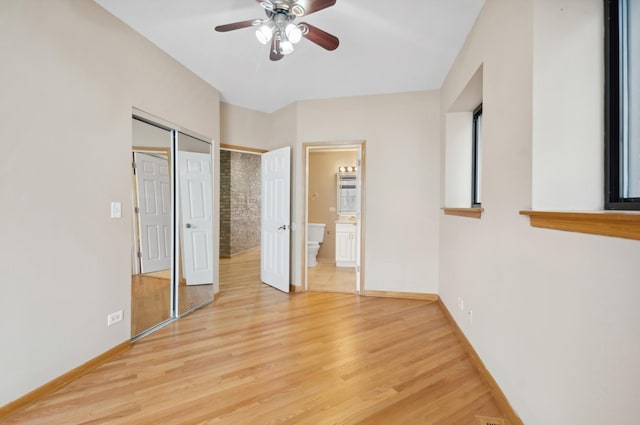 unfurnished bedroom with ceiling fan, light wood-type flooring, ensuite bathroom, and a closet