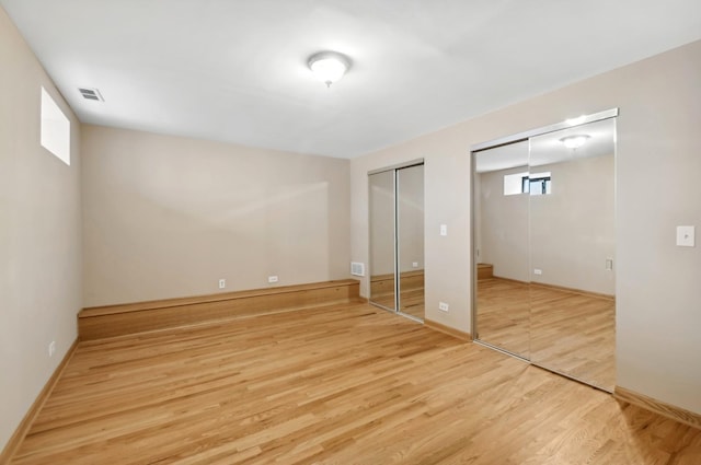 unfurnished bedroom with multiple closets and light hardwood / wood-style flooring