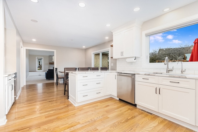 kitchen with white cabinets, dishwasher, light wood-type flooring, and kitchen peninsula