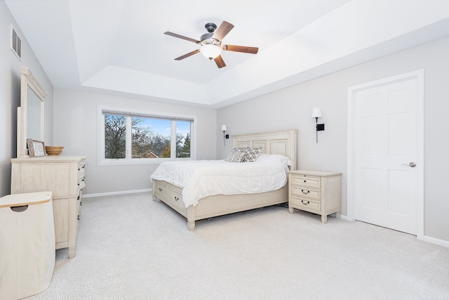 bedroom with a tray ceiling, ceiling fan, and light carpet