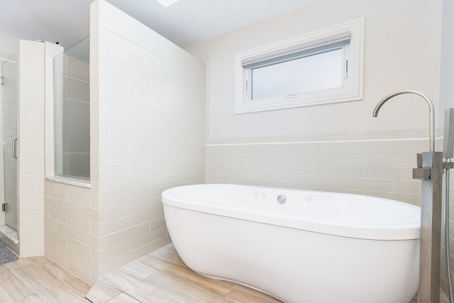 bathroom with hardwood / wood-style floors, plus walk in shower, and tile walls