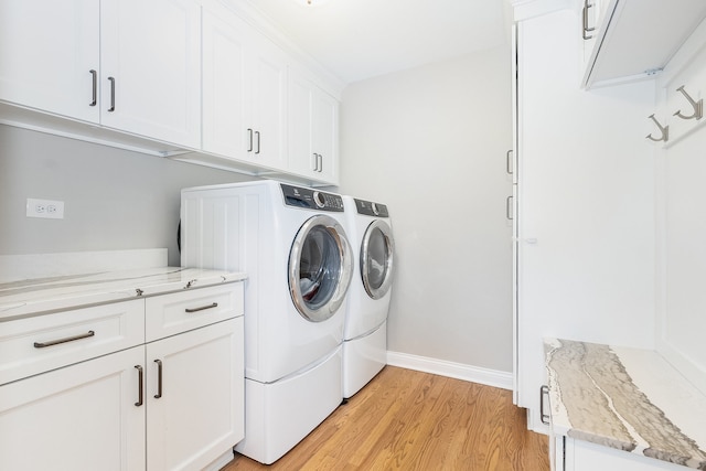 clothes washing area featuring light hardwood / wood-style floors, cabinets, and washing machine and clothes dryer