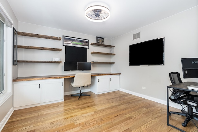 office space with built in desk and light hardwood / wood-style flooring