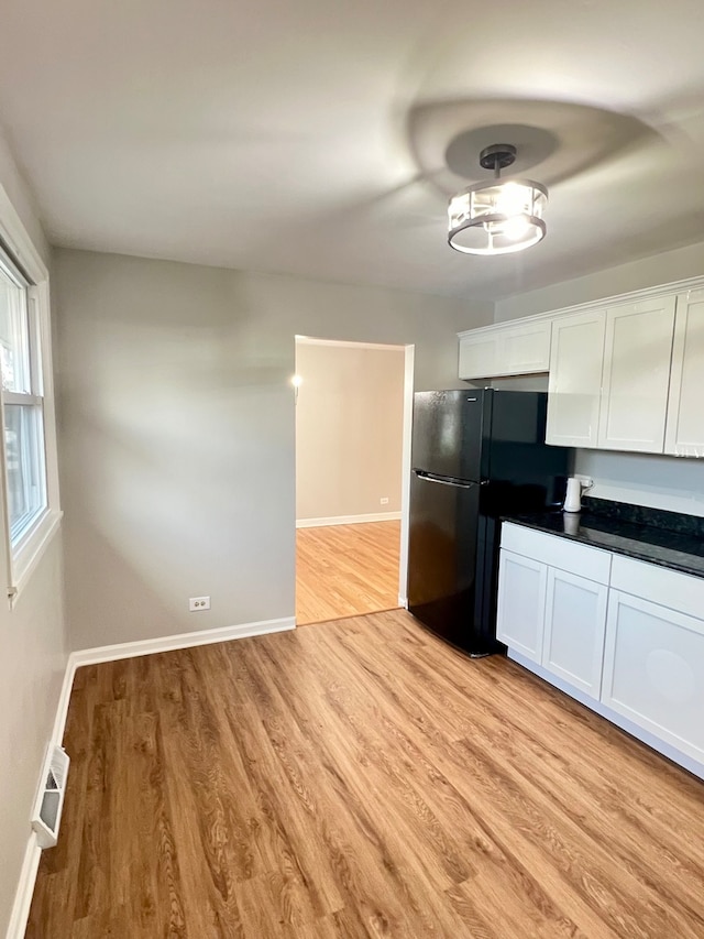 kitchen with black refrigerator, light hardwood / wood-style flooring, and white cabinets