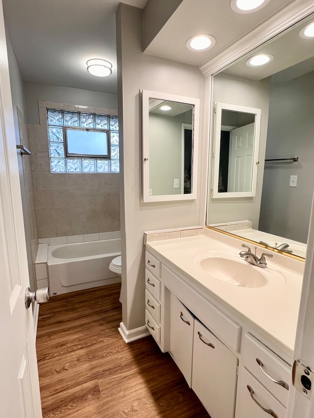 full bathroom featuring hardwood / wood-style floors, vanity, toilet, and tiled shower / bath combo