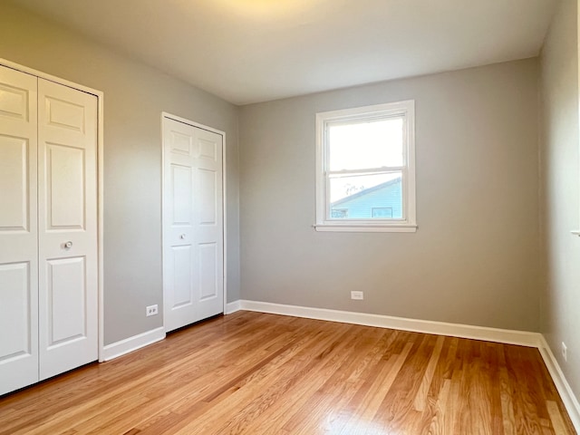 unfurnished bedroom featuring light hardwood / wood-style flooring and two closets