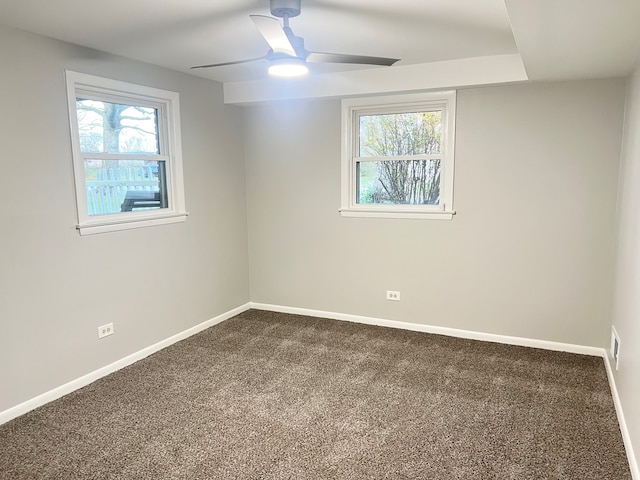 carpeted spare room featuring a wealth of natural light and ceiling fan