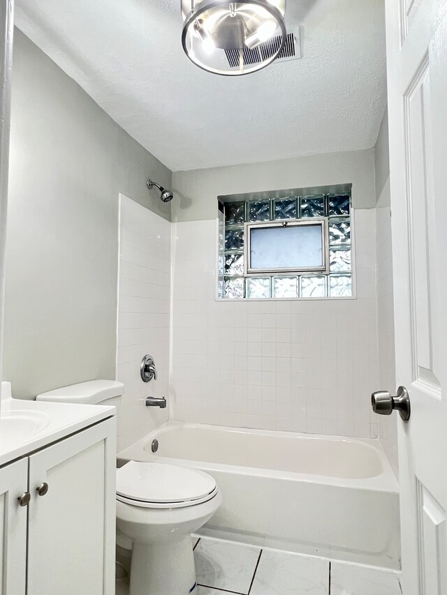 full bathroom with a textured ceiling, vanity, tiled shower / bath combo, tile patterned flooring, and toilet