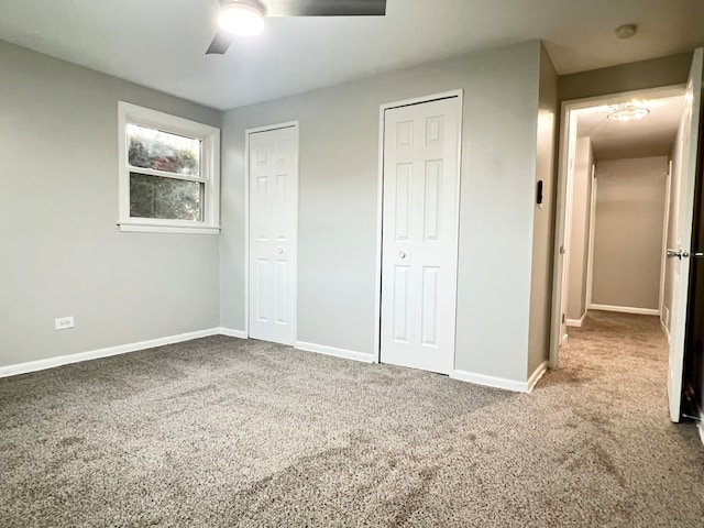 unfurnished bedroom with carpet floors, ceiling fan, and multiple closets