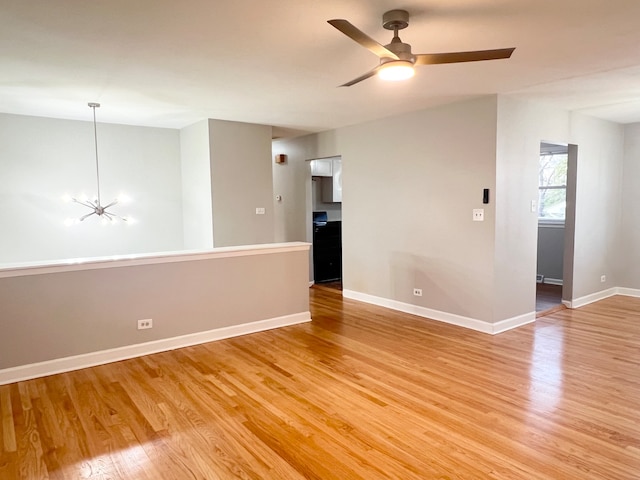 unfurnished room featuring ceiling fan with notable chandelier and light wood-type flooring