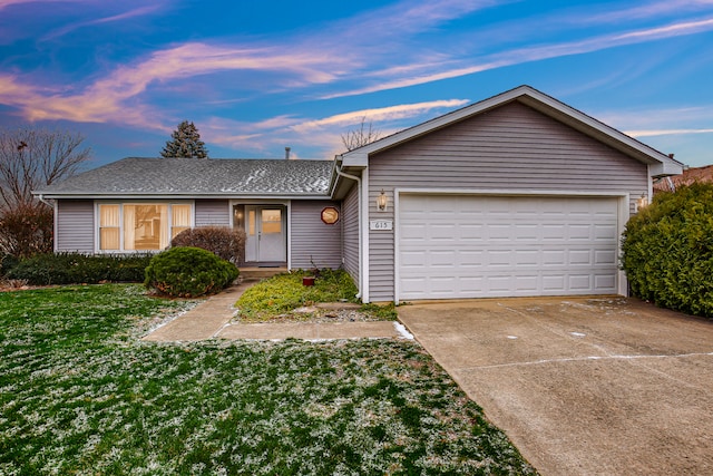 ranch-style home featuring a lawn and a garage