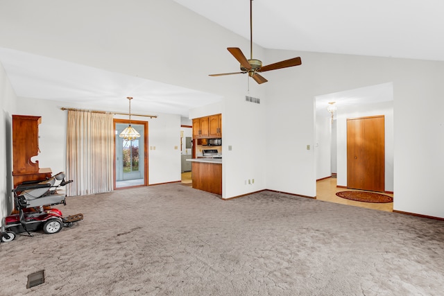 unfurnished living room with ceiling fan with notable chandelier, light carpet, and high vaulted ceiling