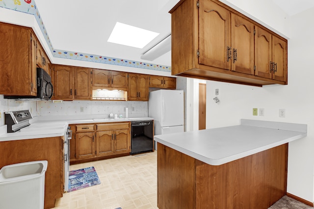 kitchen featuring black appliances, sink, a skylight, tasteful backsplash, and kitchen peninsula