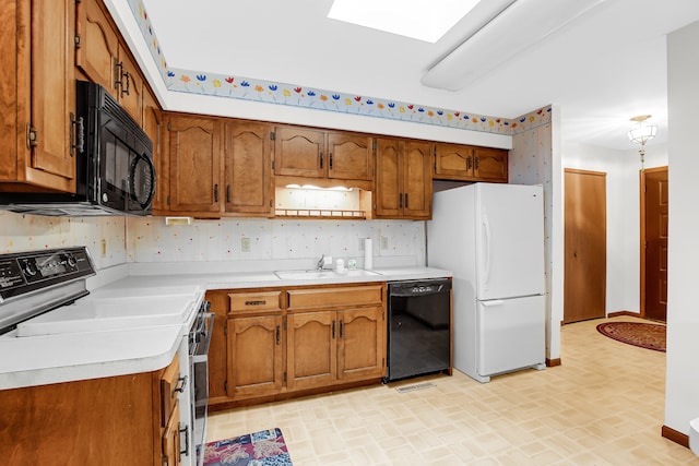 kitchen with black appliances, sink, and a skylight