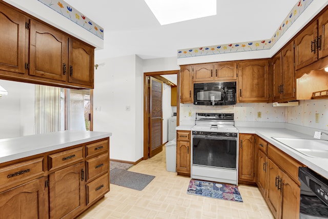 kitchen featuring black appliances, sink, and a skylight