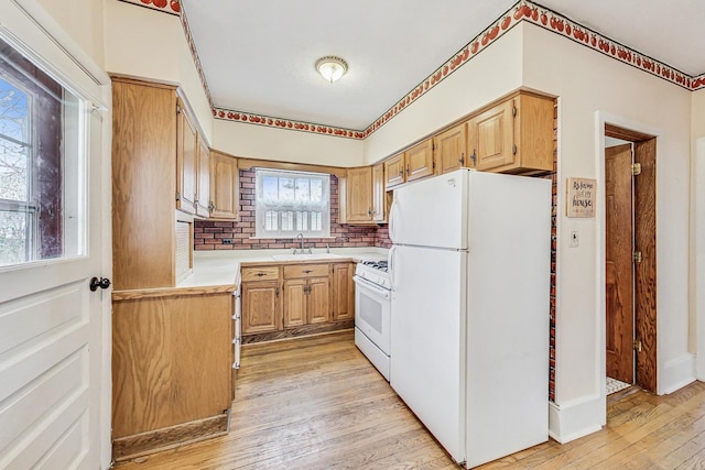 kitchen featuring light brown cabinets, white appliances, light hardwood / wood-style flooring, and sink