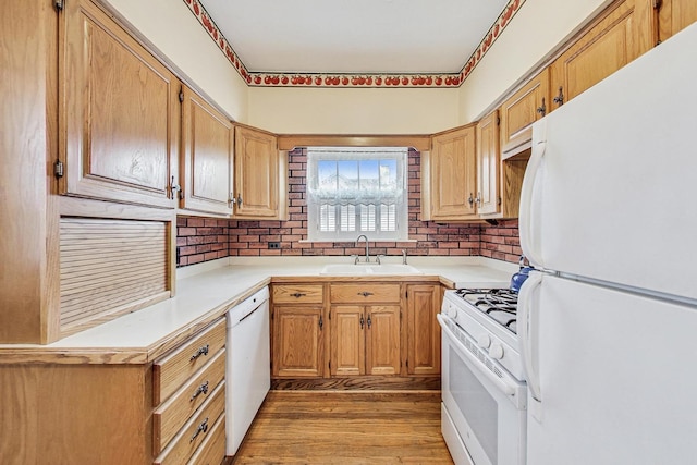 kitchen with white appliances, sink, and light hardwood / wood-style flooring