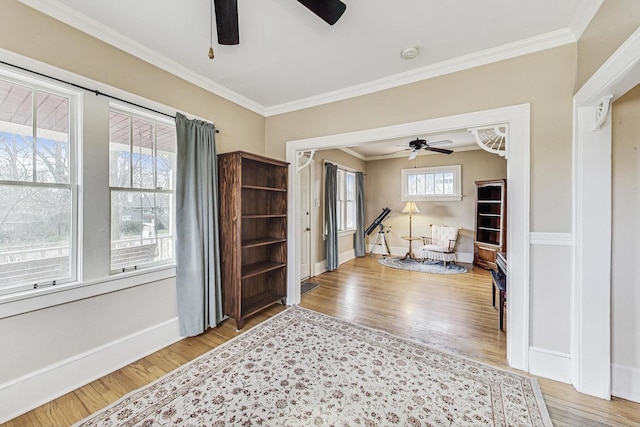 interior space with wood-type flooring, ceiling fan, and ornamental molding