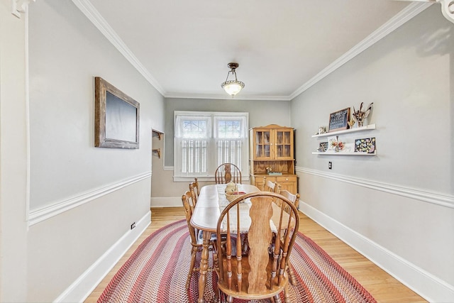 dining area with light hardwood / wood-style floors and ornamental molding