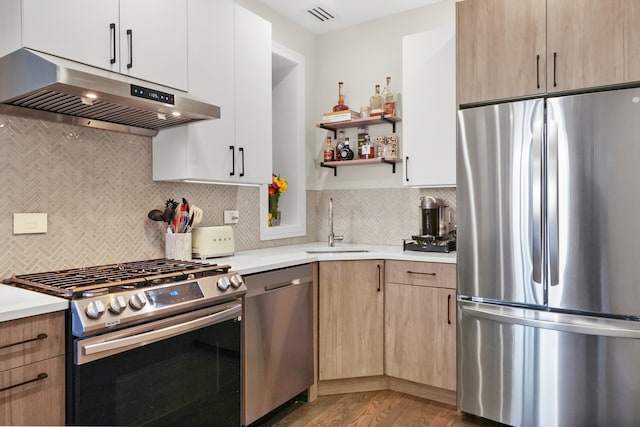 kitchen featuring decorative backsplash, appliances with stainless steel finishes, light wood-type flooring, and sink