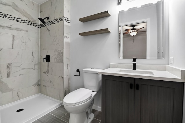 bathroom featuring tiled shower, ceiling fan, vanity, and toilet