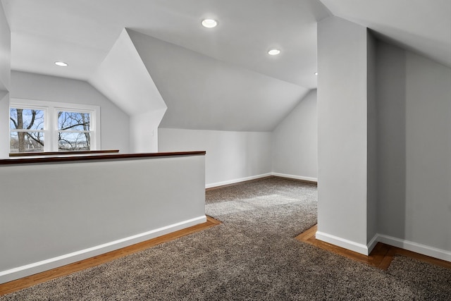 bonus room with dark colored carpet and vaulted ceiling