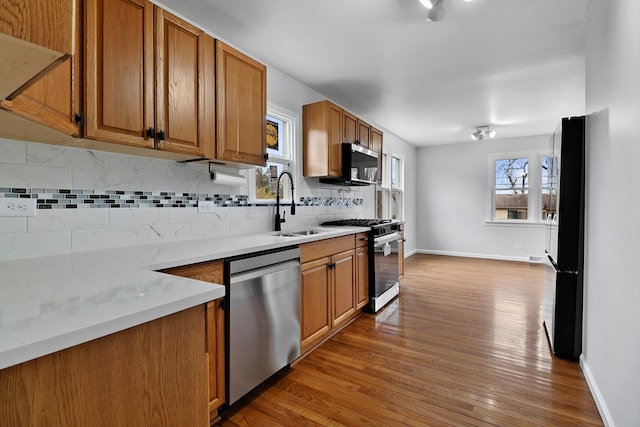 kitchen featuring wood-type flooring, backsplash, stainless steel appliances, and sink