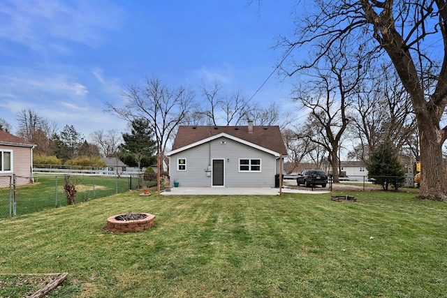 back of property with a yard, a patio, and a fire pit