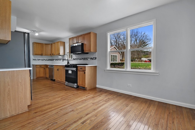 kitchen featuring light hardwood / wood-style floors, sink, backsplash, and appliances with stainless steel finishes