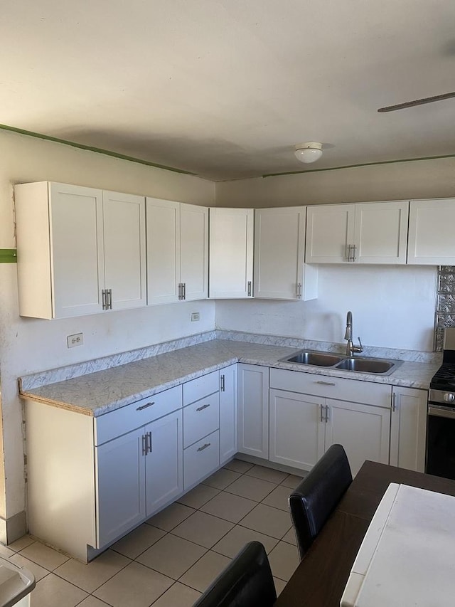 kitchen with light tile patterned floors, white cabinets, stainless steel range with gas stovetop, and sink