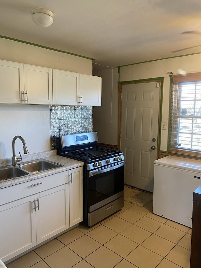 kitchen with sink, fridge, stainless steel range with gas cooktop, and white cabinetry