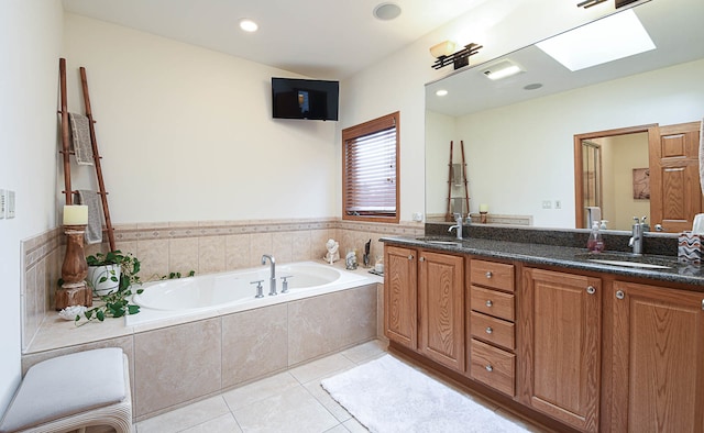 bathroom with tiled bath, vanity, a skylight, and tile patterned floors