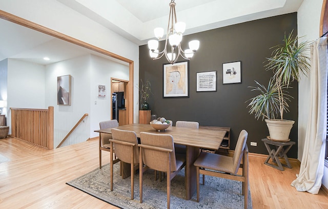 dining area with light hardwood / wood-style floors and a chandelier