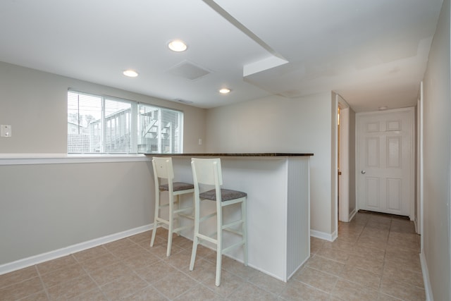 kitchen featuring a kitchen bar, kitchen peninsula, and light tile patterned flooring