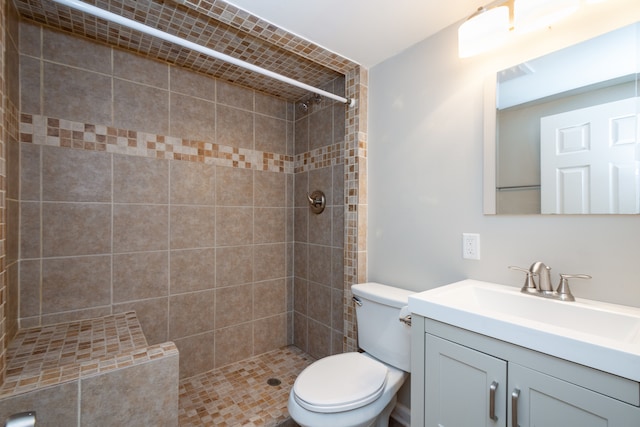 bathroom featuring vanity, toilet, and tiled shower