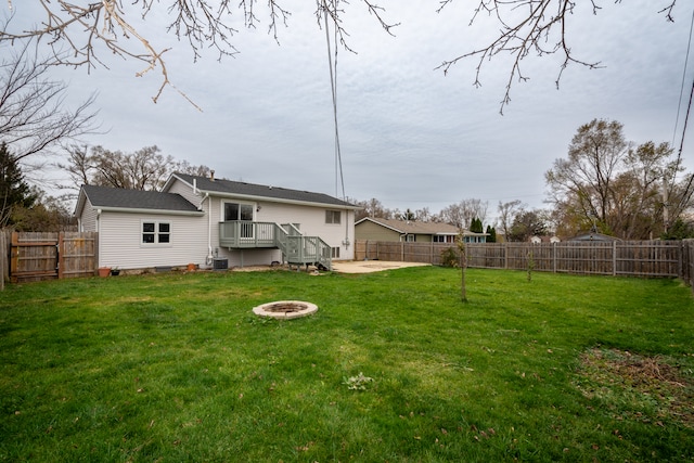 rear view of house featuring a lawn, a wooden deck, and an outdoor fire pit