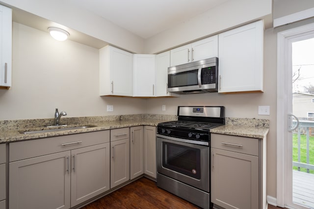 kitchen featuring dark hardwood / wood-style floors, light stone countertops, sink, and appliances with stainless steel finishes