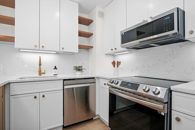 kitchen with light stone countertops, white cabinetry, sink, stainless steel appliances, and tasteful backsplash