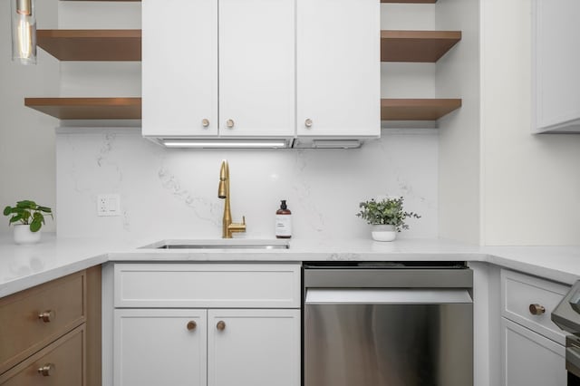 kitchen with tasteful backsplash, stainless steel dishwasher, sink, white cabinets, and hanging light fixtures