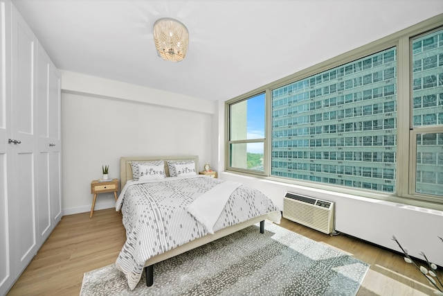 bedroom featuring a wall mounted air conditioner and light wood-type flooring