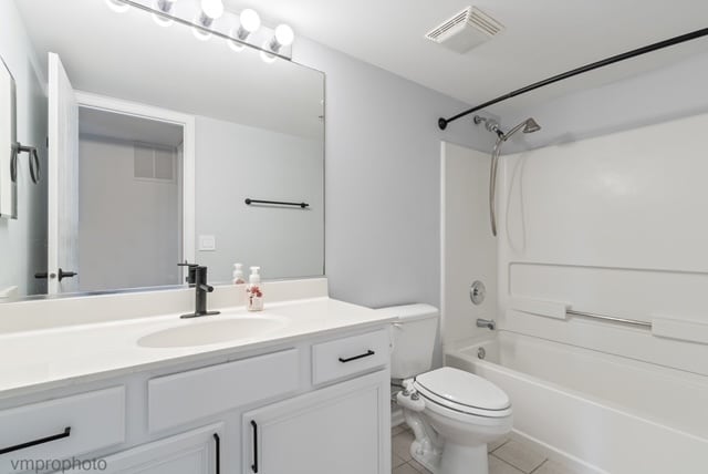 full bathroom with washtub / shower combination, vanity, tile patterned floors, and toilet